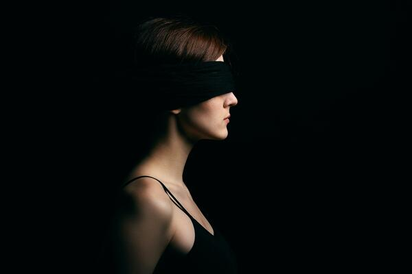 Woman wearing black blindfold on dark background representing losing my vision and why community matters for blind individuals supported in Jacksonville FL